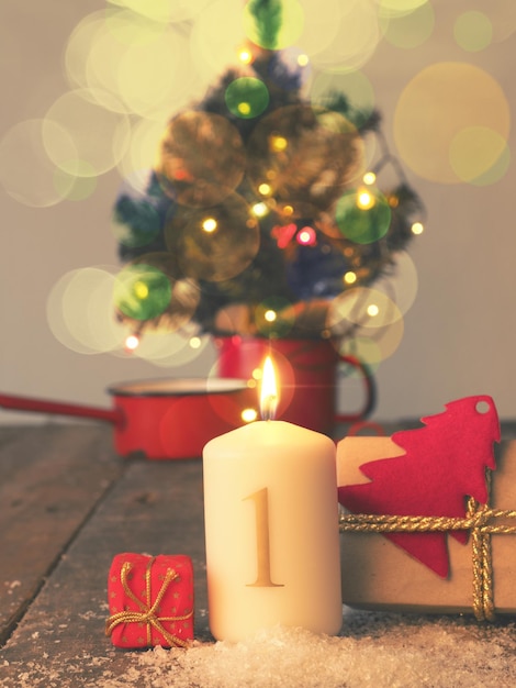 Foto close-up de vela iluminada e caixa de presentes pela árvore de natal