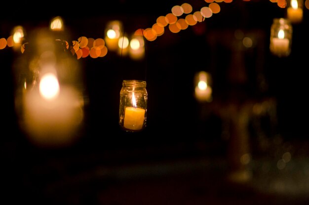 Close-up de velas acesas em frascos à noite