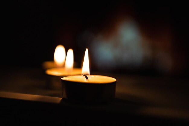 Close-up de velas brancas queimando no espelho com luz dourada de fundo borrão apagão