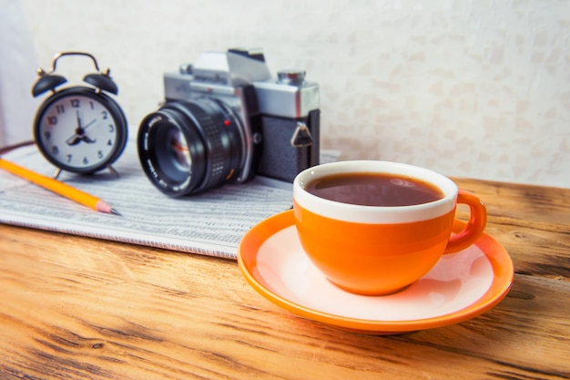 Close-up de xícara de café com câmera e despertador na mesa