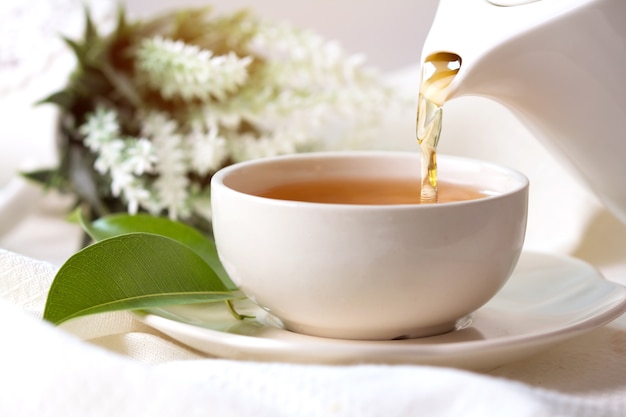 Close-up derramando chá preto quente em um copo de chá branco, conceito de tempo de cerimônia do chá