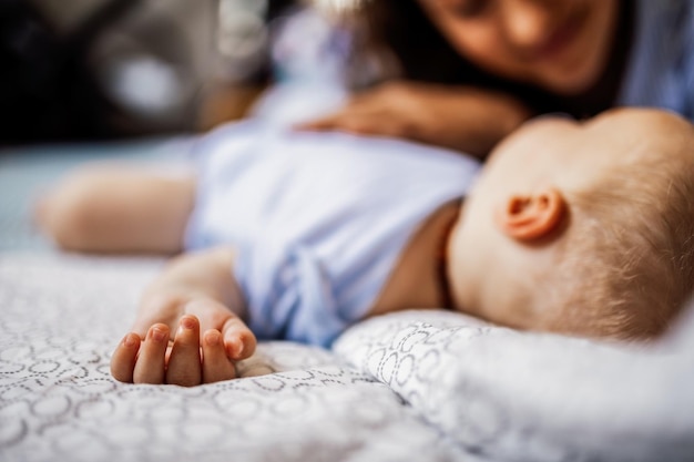 Foto close-up do bebê dormindo na cama enquanto a mãe está olhando para ela