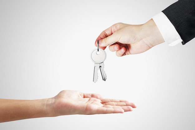 Close-up do empresário entregando as chaves no fundo branco Investimento imobiliário e conceito de compra
