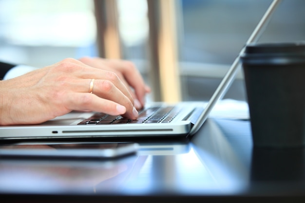 Close-up do homem de negócios de mão usando o laptop para trabalhar no escritório.