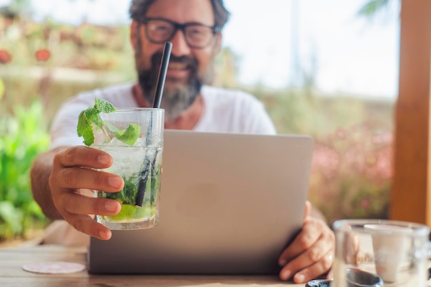 Close-up do homem nand oferecendo coquetel mohito no café após uma sessão de trabalho de laptop Conceito de liberdade do escritório e trabalho moderno alternativo feliz Pessoas do sexo masculino felizes bebem e trabalham ao ar livre