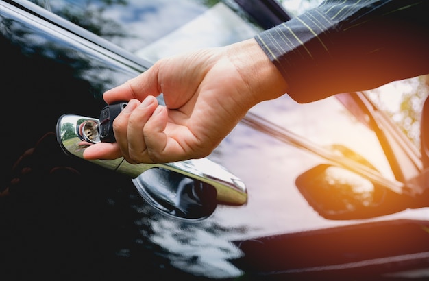 Foto close-up do homem que abre uma porta de carro. mão no punho. empresário está abrindo um carro.