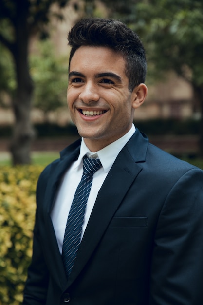 Foto close-up do jovem sorridente no jardim com terno e gravata