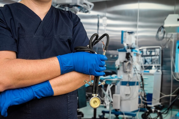 Close-up do médico do sexo masculino usa estetoscópio uniforme azul escuro e luvas na sala de emergência Profissionais de saúde contra surto de coronavírus