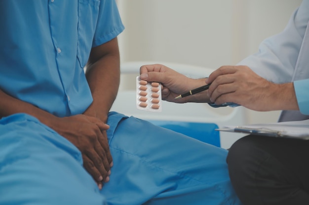 Close-up do médico sentado ao lado da cama de um paciente do sexo masculino no hospital