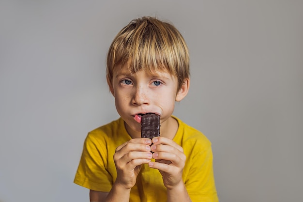 Close-up do menino comendo uma barra de chocolate