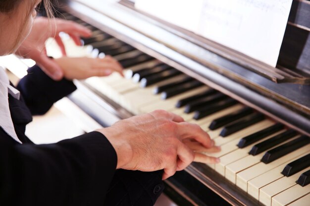 Close-up do músico homem e menina mãos tocando piano