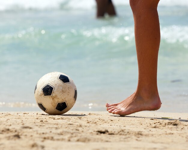 Foto close-up do pé masculino jogando futebol na areia