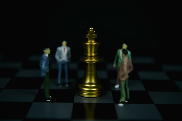 Foto close-up do rei em meio a estatuetas no tabuleiro de xadrez contra um fundo desfocado