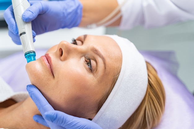 Close-up do retrato de uma paciente de meia-idade submetida a um tratamento facial de peeling de microdermoabrasão hidro vácuo