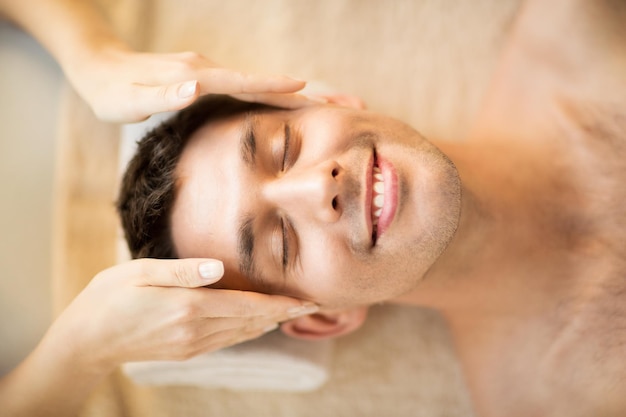 close-up do rosto do homem em salão de spa recebendo massagem facial