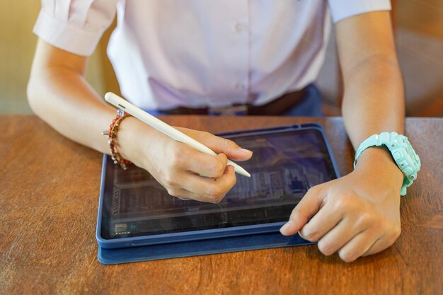 Foto close-up e corte de mãos do aluno usando e estudando no tablet na escola