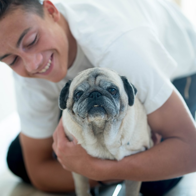 Close up e retrato de dois melhores amigos juntos em casa - adolescente olhando com amor para seu pug - conceito de animal de estimação e cachorro doméstico