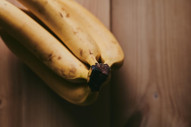 Foto close-up eines bündels bananen auf einem hölzernen küchentischhintergrund