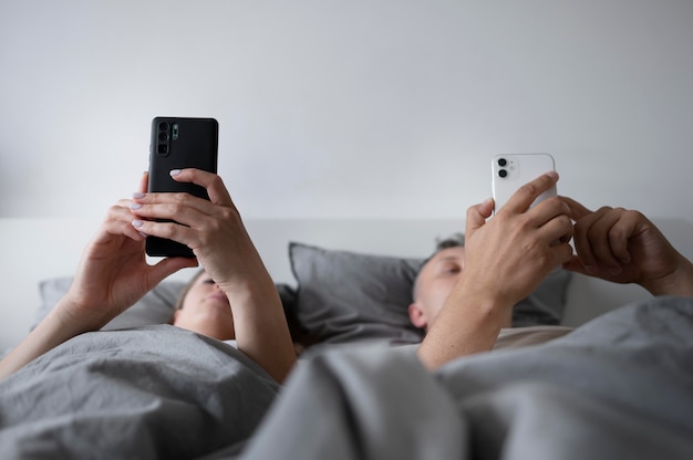 Foto close-up em casais em telefones no quarto