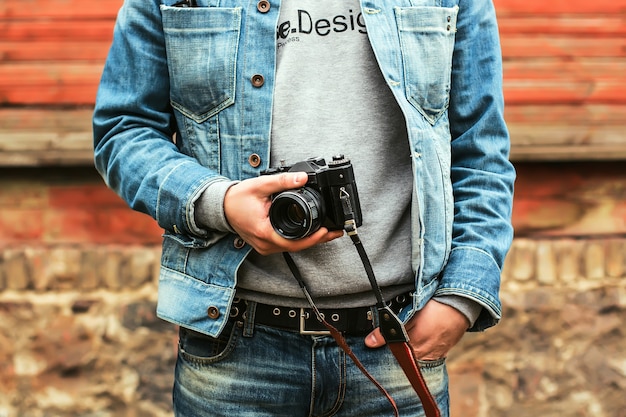 close-up em um homem segurando uma câmera vintage ao ar livre