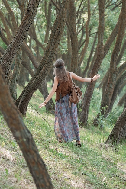 Close-up em uma jovem hippie parada entre as árvores na floresta