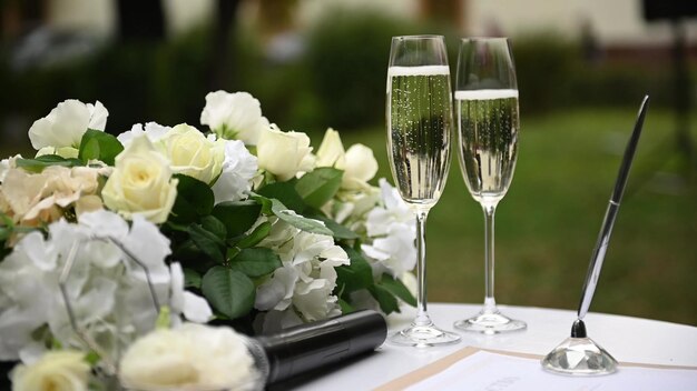 Close-up, em uma mesa redonda de madeira branca em um dia de sol, há uma linda caixa de vidro multifacetada, decorada com flores, para alianças de casamento