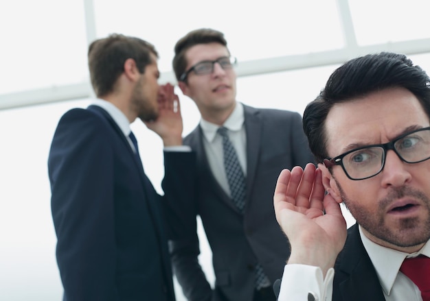 Foto close-up. empresário bisbilhotando uma conversa entre colegas. o conceito de fofoca