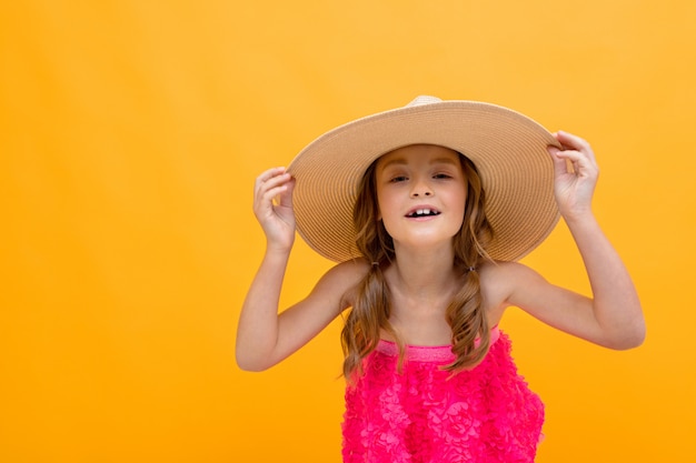 Foto close-up encantadora jovem bonito com um chapéu de palha na cabeça em uma parede laranja