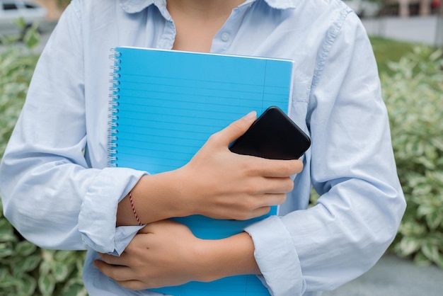 close-up estudantes mulher segurando livros e celular na mão