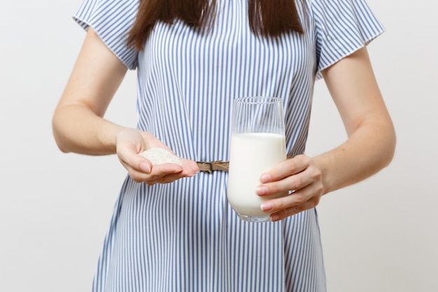 Close-up foto recortada de mulher segura nas mãos leite de arroz em vidro, punhado de arroz isolado no fundo branco. Nutrição adequada, bebida vegetariana vegana, conceito de dieta de estilo de vida saudável. Copie o espaço.