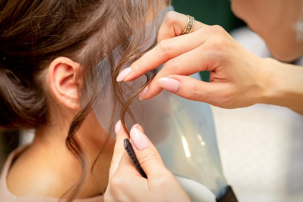 Close Up Friseur Stylist macht Frisur für eine junge Frau in einem Schönheitssalon.