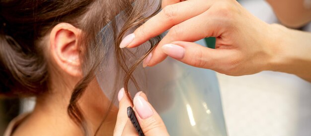 Close Up Friseur Stylist macht Frisur für eine junge Frau in einem Schönheitssalon.