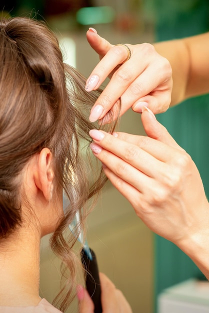 Close Up Friseur Stylist macht Frisur für eine junge Frau in einem Schönheitssalon.