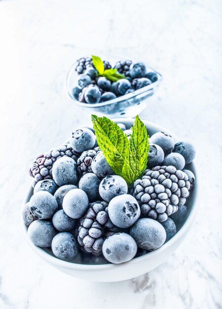 Close-up gefrorene Blaubeeren und Brombeeren mit Minzblättern.