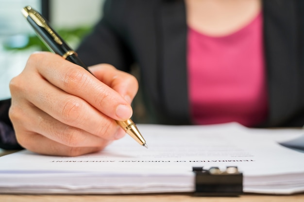 Close Up Geschäftsfrau Hand unterzeichnen Vertragsdokument am Schreibtisch in einem Geschäftsbüro