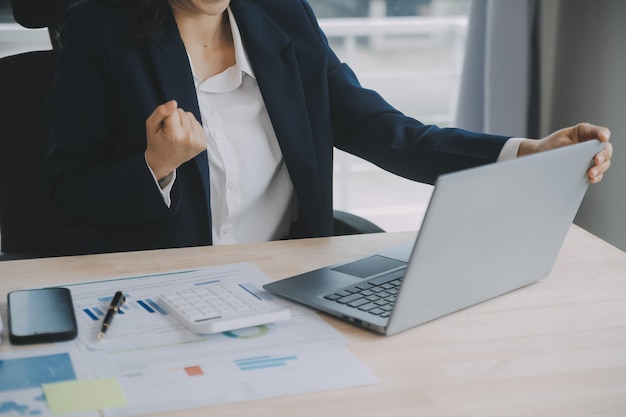 Close-up Geschäftsfrau mit Taschenrechner und Laptop für Mathematik Finanzen auf Holzschreibtisch Steuerbuchhaltung Statistik und analytisches Forschungskonzept