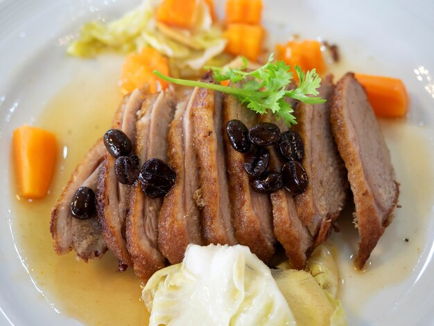 Close-up geschnittene gebratene Ente mit Kaffeebohnensauce auf weißem Teller