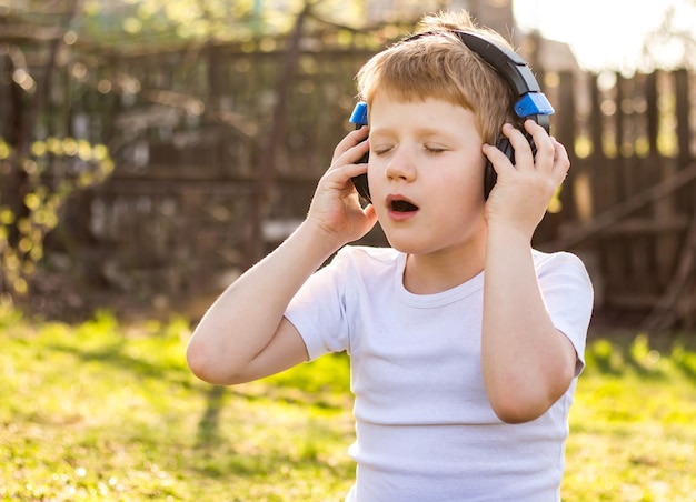 Close-up-Gesicht Kinderjunge, der Musik über Kopfhörer hört, die sich draußen in der Natur entspannen