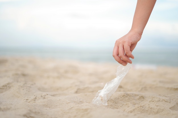 Foto close up hand holen sie die plastiktüte vom strand
