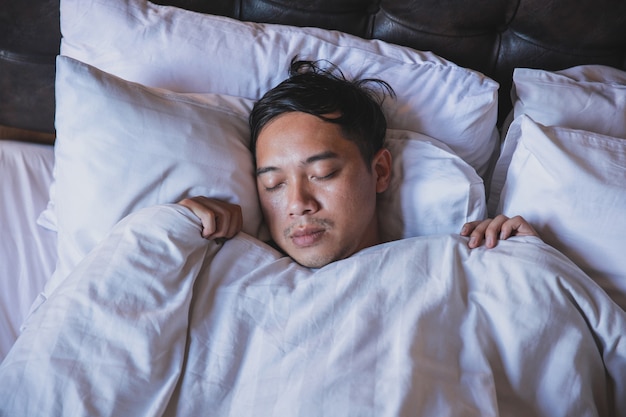 Close-up homem dormindo na cama com cobertor branco