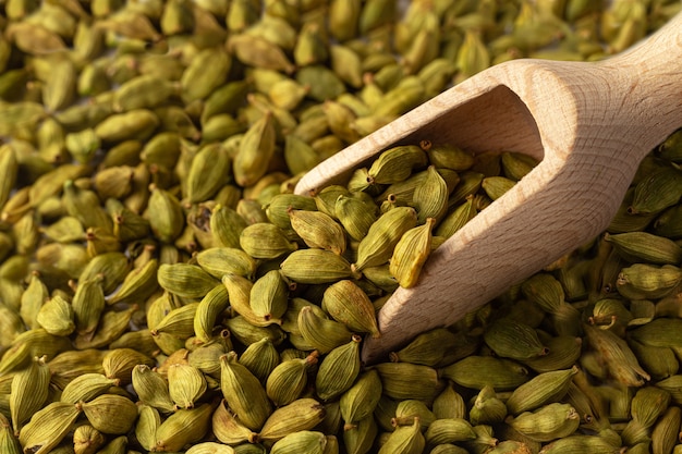 Close up horizontal em sementes de cardamomo com colher de madeira