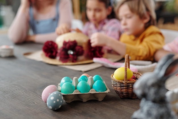 Close-up de huevos de Pascua pintados sobre la mesa de madera preparada para la Pascua con la familia en el fondo