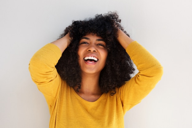 Close-up jovem alegre americana africano rindo com as mãos no cabelo encaracolado