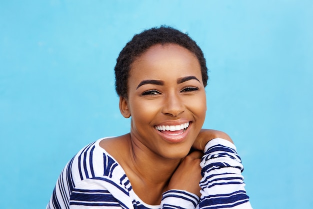 Close-up jovem negra moda mulher sorrindo contra parede azul