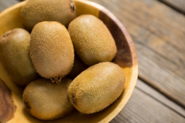 Close-up de kiwis en un recipiente sobre la mesa de madera