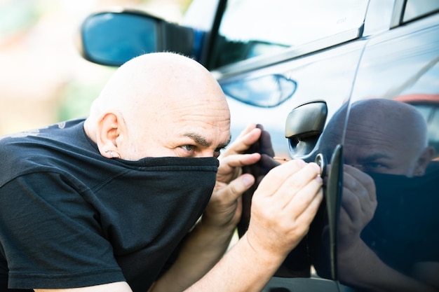 Close-up ladrão roubando carro desbloqueado homem tentando invadir dentro do homem vestido de preto wi