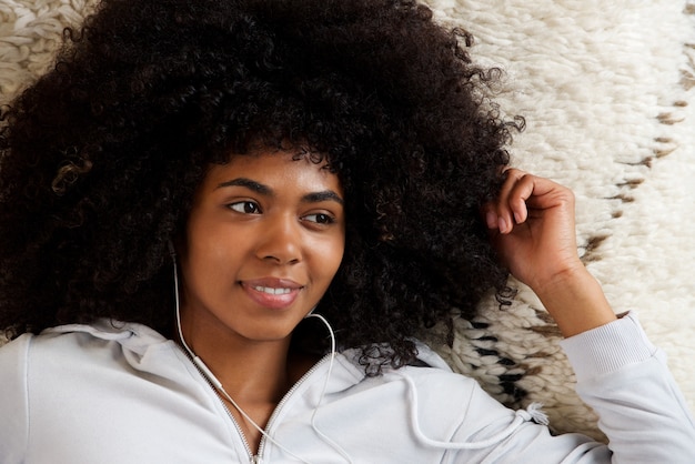 Close-up linda garota afro-americana com cabelo longo encaracolado e ouvindo música em fones de ouvido