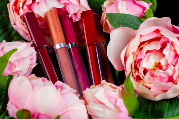Close up Lipgloss-Sticks und rosa Blumen bilden Werkzeuge
