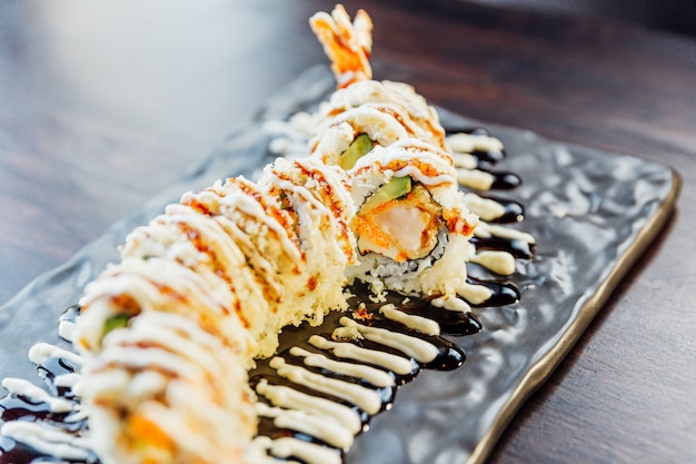 Close-up Maki Sushi mit Reis, Shrimp Tempura, Avocado und Käse in bedecktem knusprigem Tempura-Mehl. Belag mit Teriyaki-Sauce und Mayonnaise.
