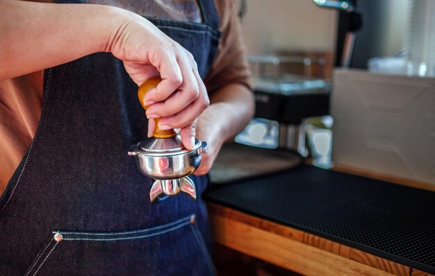 Foto close-up de la mano barista haciendo café con prensas manuales café molido usando manipulación en el café